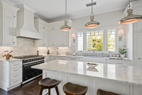 a white kitchen with a large island with two bar stools at Minimalistic 1885 Queen Anne Cottage 2B-2B Upper Level Flat in Alameda in Alameda