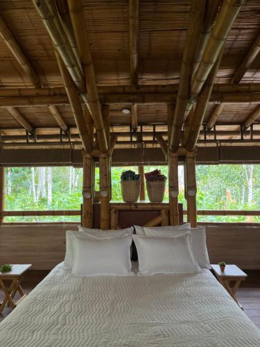 um quarto com uma cama com lençóis brancos e almofadas em Oasis Santuario de Naturaleza em Ibagué