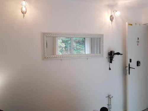 een spiegel op een witte muur met een raam bij Chez Lisa & Olivier in Athis-Mons