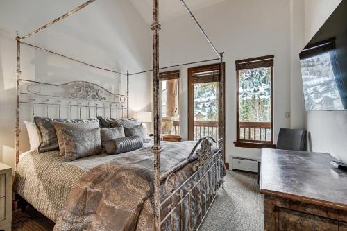 a bedroom with a bed and a desk and windows at Elkhorn Lodge in Avon