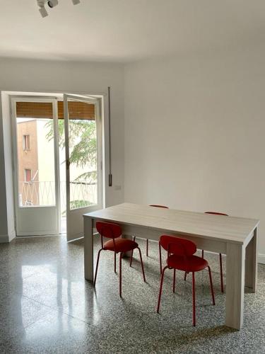 une table en bois avec quatre chaises rouges dans la chambre dans l'établissement Lucilio - intero appartamento, à Rome