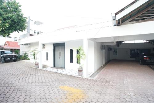 een wit gebouw met een parkeerplaats ervoor bij Hotel Bhakti in Padang