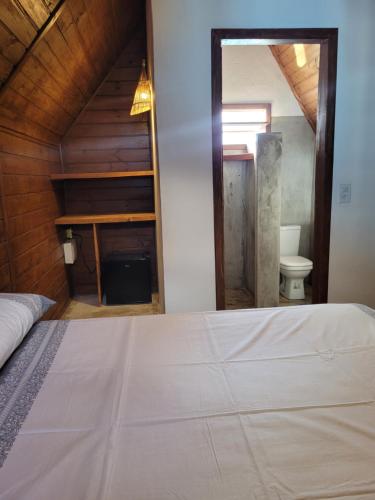 a bedroom with a bed and a bathroom with a toilet at Chalés Conexão Bahia in Amontada