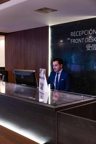 a man in a suit standing at a reception desk at Best Western PLUS Plaza Florida & Tower in Irapuato