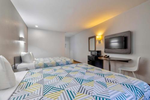 a hotel room with two beds and a flat screen tv at Motel 6 Little Rock AR South in Little Rock