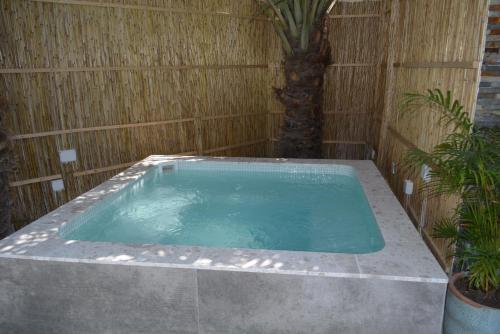 a hot tub in a wooden wall with a palm tree at Dar 66 Pool Chalets with Jacuzzi in Ras al Khaimah