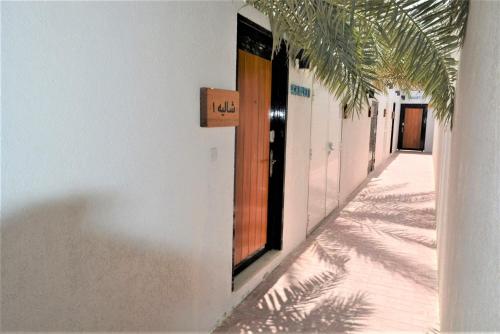 a hallway with a door in a building with palm trees at Dar 66 Pool Chalets with Jacuzzi in Ras al Khaimah