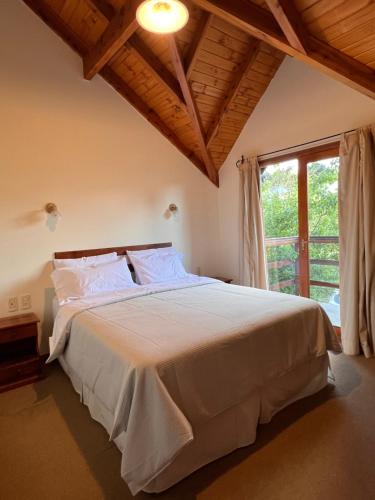 a bedroom with a large white bed with a window at Bandurria in Esquel