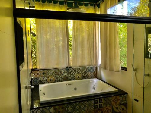 a bath tub in a bathroom with a window at Casa completa próxima a Ouro Preto! Amarantina in Ouro Preto