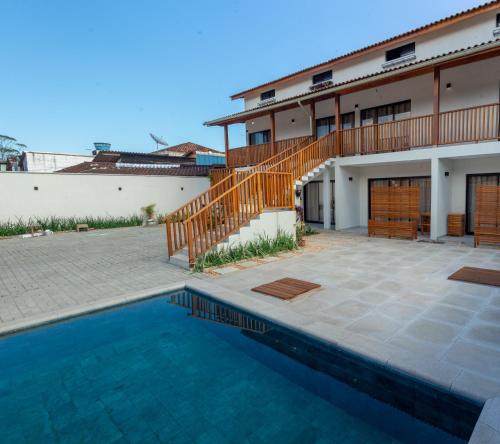a villa with a swimming pool and a house at Carolekerry Apartments in São Sebastião