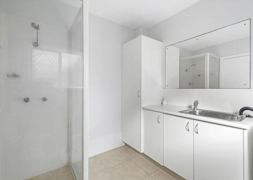 a white bathroom with a sink and a mirror at Adrift, 5B Scott Street in Crescent Head