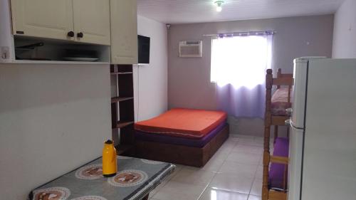 a small room with a bed and a refrigerator at Residencial Caiobá I in Matinhos