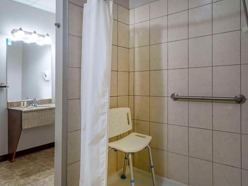 a bathroom with a chair and a shower curtain at Travelodge by Wyndham Wetaskiwin in Wetaskiwin