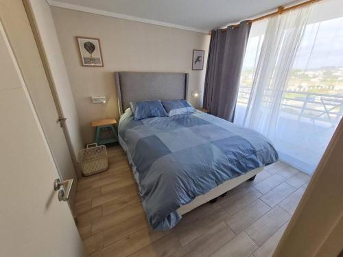 a bedroom with a bed and a large window at Depto ¡NUEVO! a pasos del mar. in La Serena