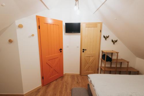 a room with a door and a bed and a tv at Nasza Chata in Duszniki Zdrój