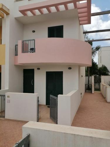Cette maison blanche dispose d'un balcon avec deux portes. dans l'établissement Case in Residence Torre dell'Orso, à Torre dell'Orso