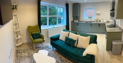 a living room with a green couch and a kitchen at Dover Castle Luxury Apartments in Kent