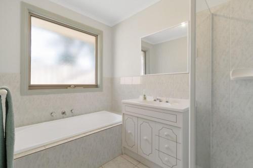 uma casa de banho branca com uma banheira, um lavatório e um espelho. em Bay Beach Beauty em Blairgowrie