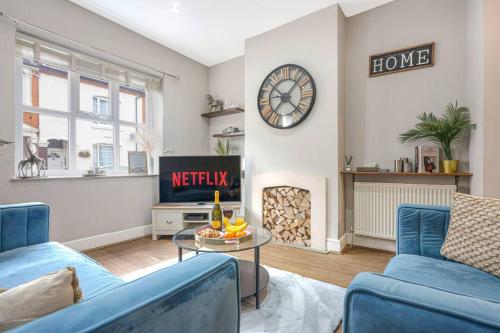 a living room with two blue couches and a clock at Central House with Parking, Pool Table, Super-Fast Wifi and Smart TV with Virgin Media and Netflix by Yoko Property in Northampton