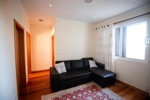 a black leather couch in a living room with a window at Casa da Montanha in Salão