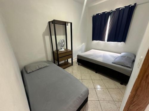 a small bedroom with two beds and a mirror at Apart 3 quartos Fernaodias in Belo Horizonte