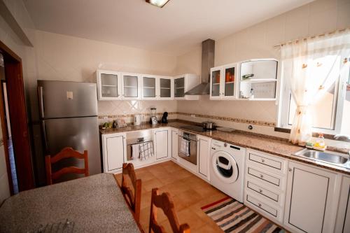 a kitchen with white cabinets and a stainless steel refrigerator at Brisas do Atlántico in Santa Maria Madalena