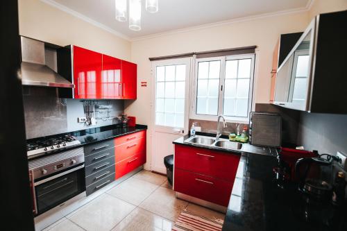 a kitchen with red cabinets and a sink at Casa da Ribeira in Senhora do Rosário