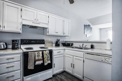 a kitchen with white cabinets and a stove top oven at Cozy 3 Bedrooms and 2 baths in Olathe sleeps 8. in Olathe