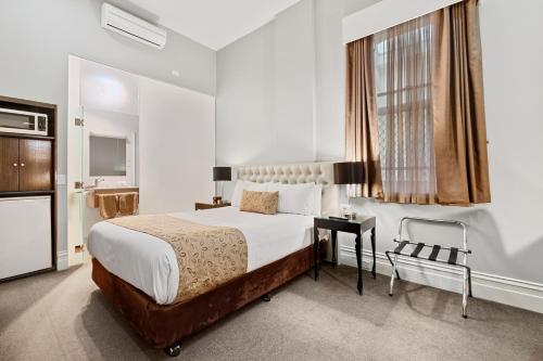 a bedroom with a bed and a desk and a window at Quality Inn The George Hotel Ballarat in Ballarat
