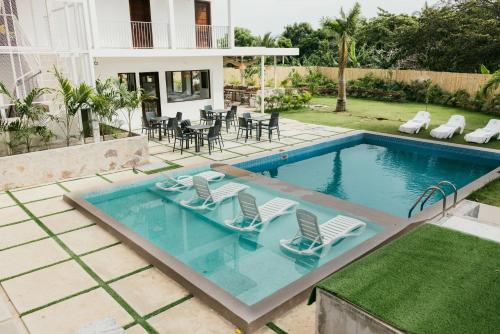 a swimming pool with chairs and a house at Hotel Pedasí Nature Paradise in Pedasí Town