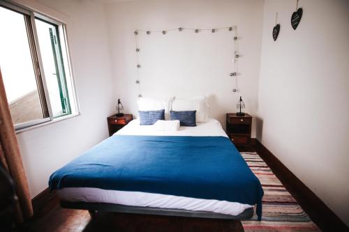 een slaapkamer met een bed met een blauwe deken bij Casa da Avo Rosa in São Vicente