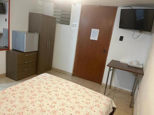 een kamer met een bed, een bureau en een tv bij HOTEL SAN VICENTE in Cajamarca