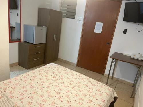 een slaapkamer met een bed, een dressoir en een bureau bij HOTEL SAN VICENTE in Cajamarca