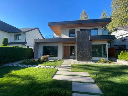 a house with a green yard with a pathway at Grand Boulevard Basement Suite in North Vancouver