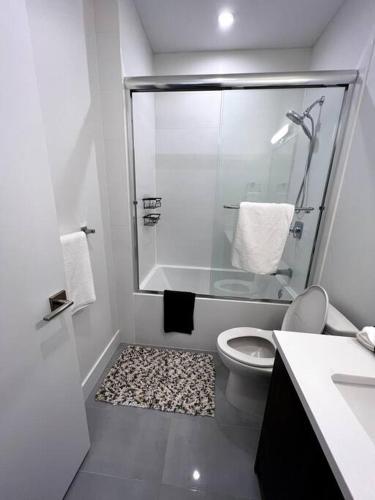 a white bathroom with a shower and a toilet at Grand Boulevard Basement Suite in North Vancouver