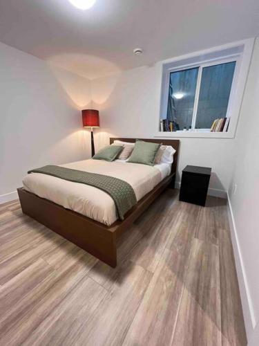 a bedroom with a bed and a window and a lamp at Grand Boulevard Basement Suite in North Vancouver
