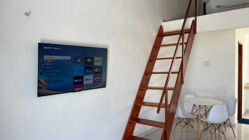Villa Suíça, Chalé Mezanino في تيانغوا: تلفزيون معلق على جدار بجانب طاولة وكراسي