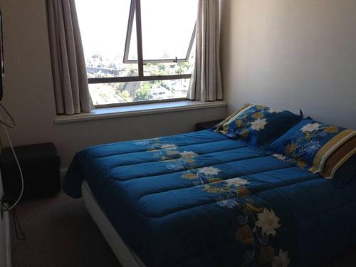 Una cama azul en un dormitorio con ventana. en Miramar, en Viña del Mar
