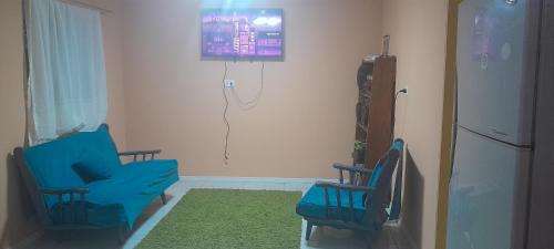 a living room with two blue chairs and a tv at Cabaña in Chillán