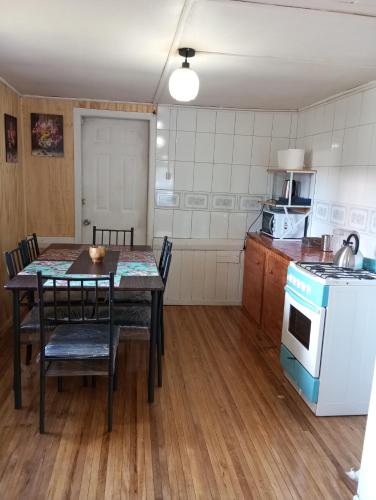 eine Küche mit einem Tisch mit Stühlen und einem Herd in der Unterkunft Las palmas in Ancud