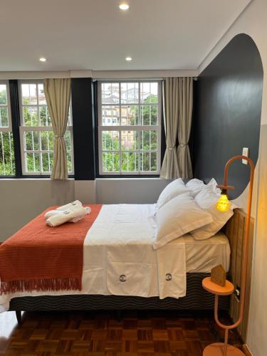 um quarto com uma cama grande e 2 janelas em Suíte Horto em Ouro Preto
