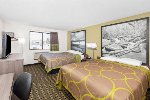 a hotel room with two beds and a flat screen tv at Super 8 by Wyndham Johnson City in Johnson City
