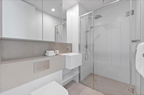 a white bathroom with a shower and a sink at Aspire Melbourne in Melbourne