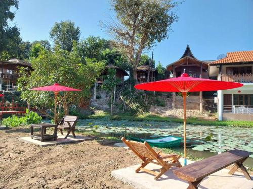a couple of chairs and umbrellas next to a pond at เรือนแฝด Brook view in Pai