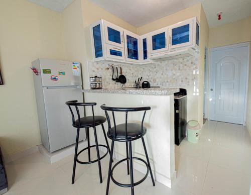 a kitchen with two bar stools and a refrigerator at APARTAMENTO FRANCO in Santo Domingo