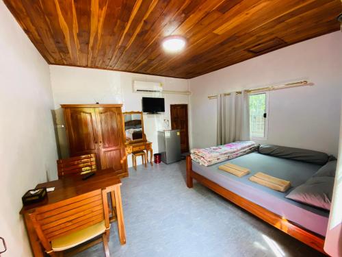 a bedroom with a bed and a desk in a room at ครัวป่าตันแอนด์โฮมสเตย์ 