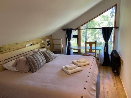 a bedroom with a large bed with two towels on it at La Colmena eco lodge in La Ensenada