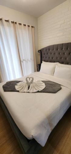 Una gran cama blanca con un arco. en Cozy Condo at Pine Suites Tagaytay with WIFI Netflix & Pool, en Tagaytay