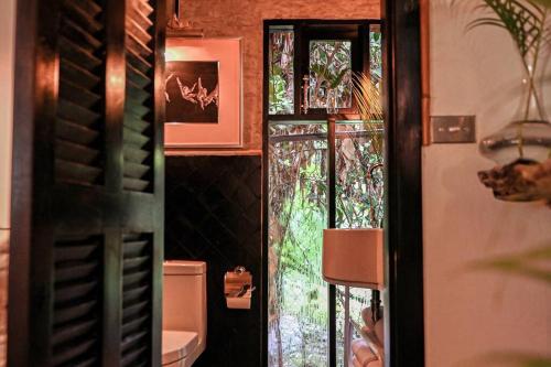 a bathroom with a toilet and a glass door at Coco Bungo - Beachside Bungalow #3 in Santa Teresa Beach