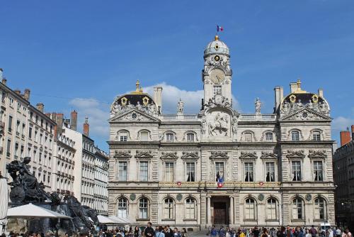 un grand bâtiment avec une tour d'horloge au sommet dans l'établissement Appartement Place des Terreaux Presqu'Ile, à Lyon